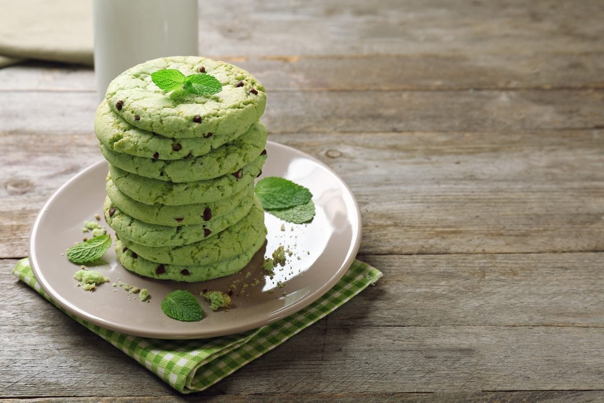 A pile of eight chocolate chip mint cookies on a plate.