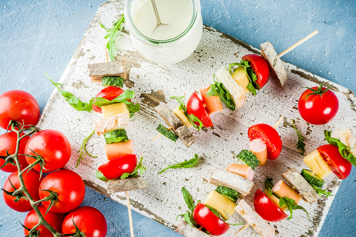 A few mini salad kebabs with bread, cherry tomato, cucumber, cheese and pieces of frankfurter.