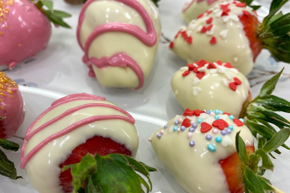 Detail of strawberries coated in chocolate or shiny frosting and decorated with sprinkles or lines drawed with pink frosting.ng.