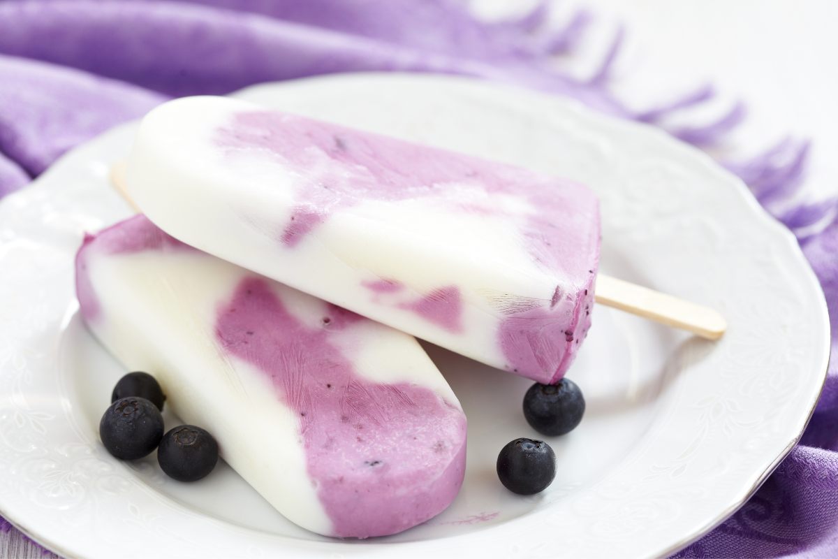 Two marbled blueberry yogurt and natural yogurt popsicles.