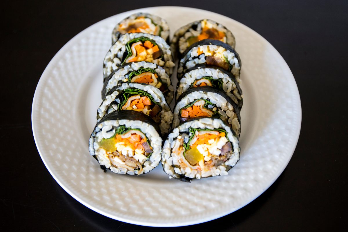 Home made nori sushi rolls on a white plate.