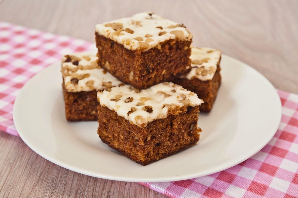 A plate with frosted carrot cake squares.