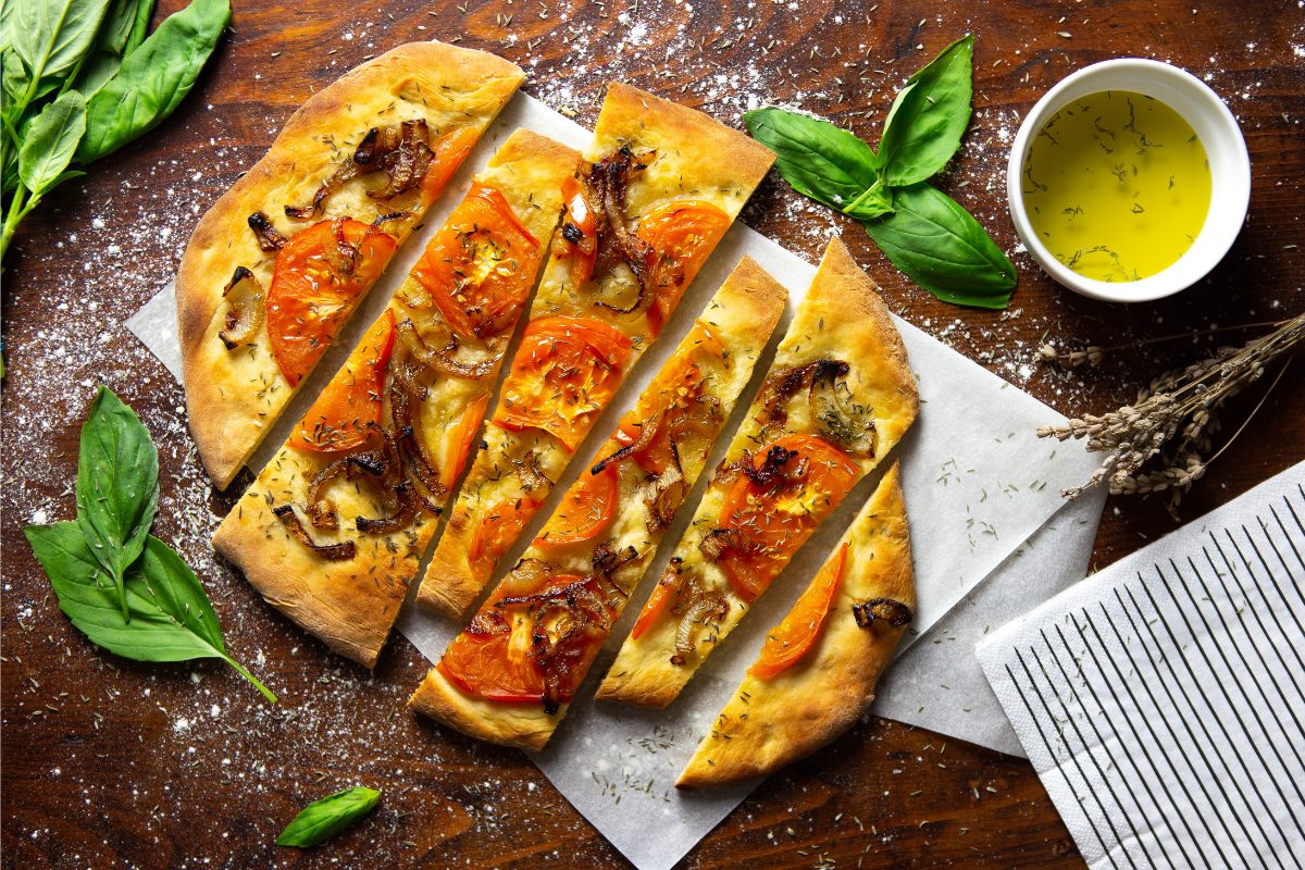 A foccacia bread with roasted onion and tomato slices.