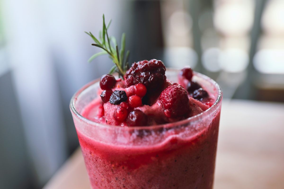 A glass of banana berry smoothie decorated with a few whole berries.