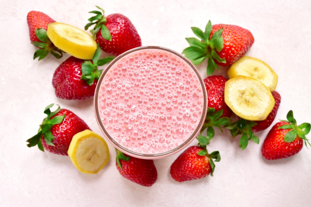 Top view of a strawberry banana smoothie surrounded with fresh strawberries and banana slices.