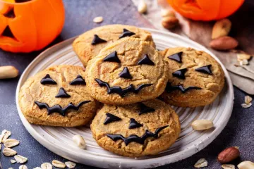 A plate with panut butter and oatmeal cookies with chocolate decorations as scary faces or pumpkin faces.