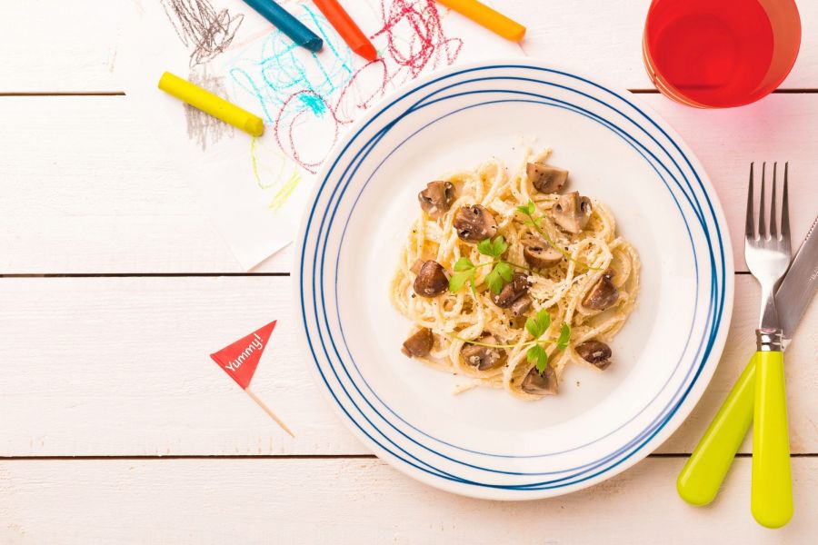 Spaghetti with mushrooms, a meal for kids, plated in a colorful way.