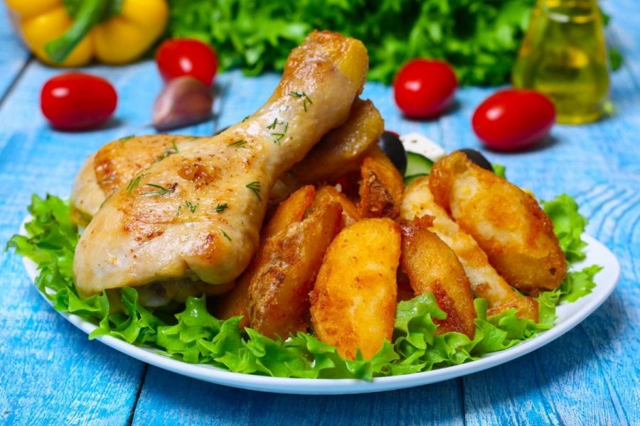 Roast chicken pieces with potato wedges over lettuce.