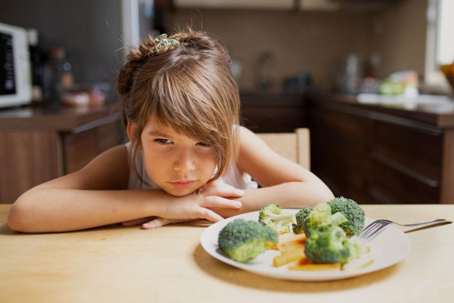Picky girl refusing to eat vegetables.