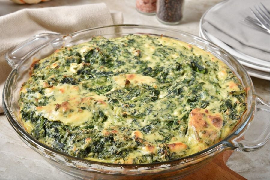 An oven shallow dish with crustless spinach quiche.