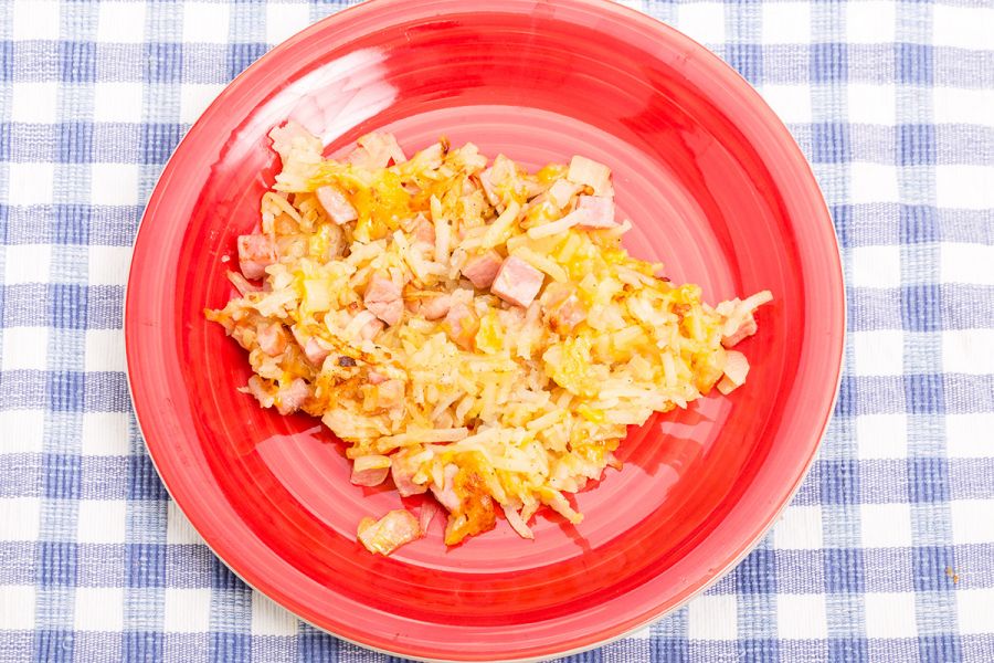 A serving of hash brown, ham and cheese casserole on a plate.