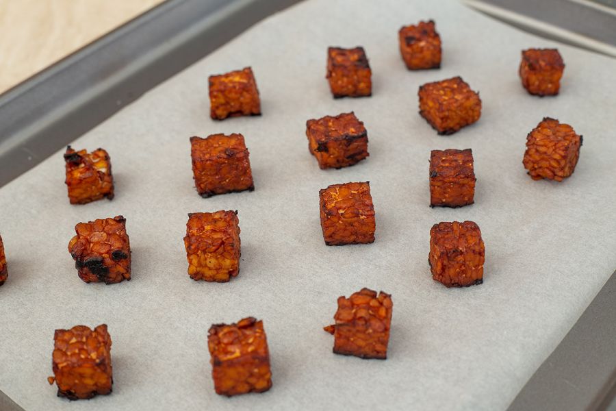 Diced tempeh baked on a paper lined oven tray.