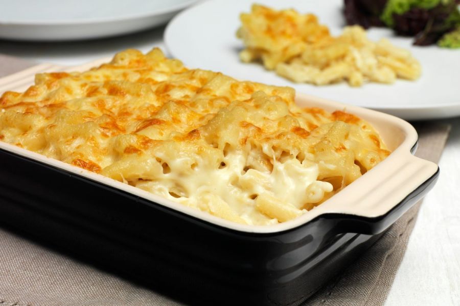 Baked macaroni cheese on a baking dish and on a plate.