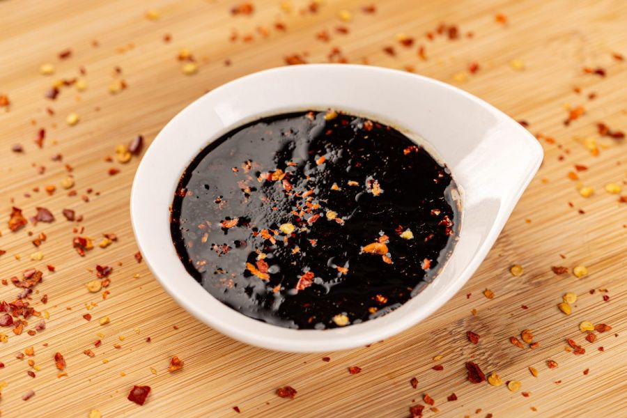 A small recipient with chili flakes spiced teriyaki sauce.