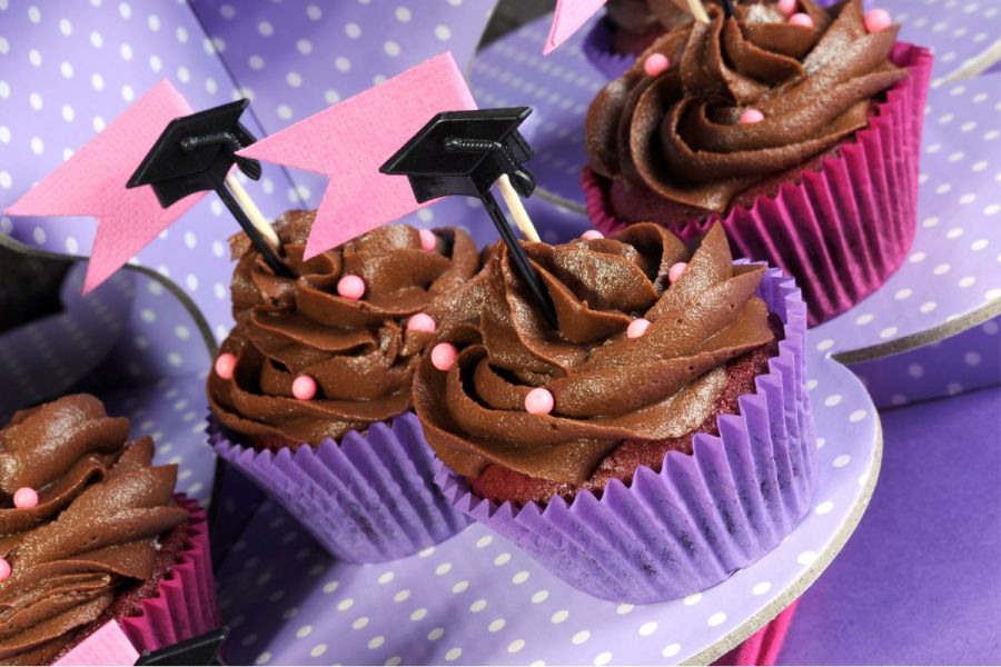 Pink and purple cupcakes decorated with graduate hats.