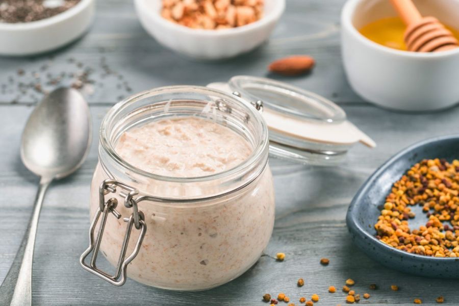 A jar with overnight oats with some of the ingredients around.