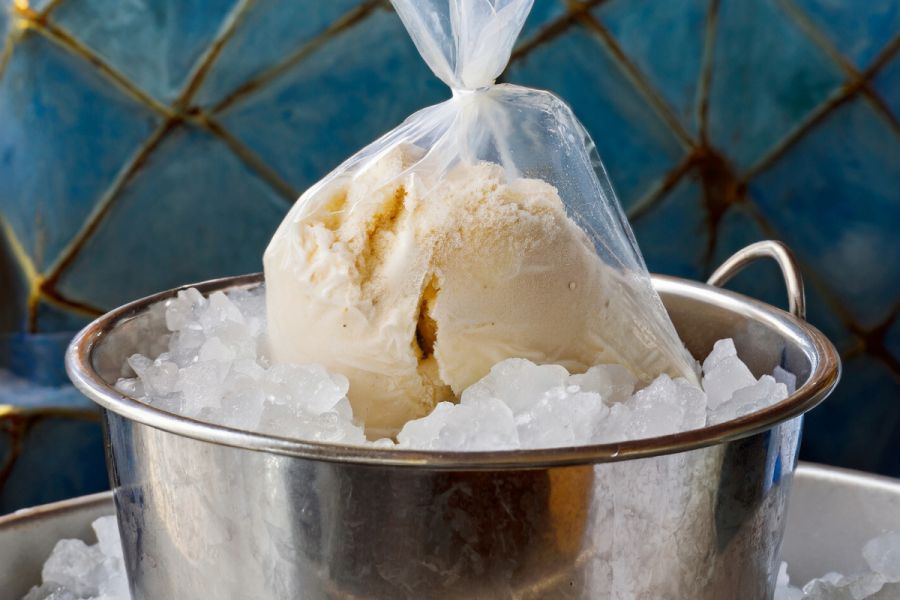 A bowl full of ice with ice cream frozen in a bag.