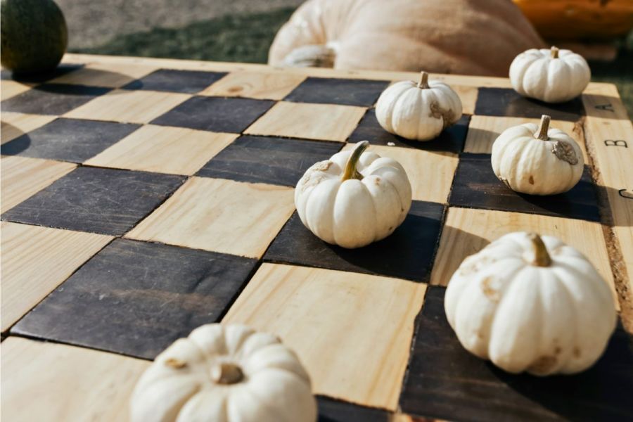 A check board with miniature pumpkins as checkers chips.